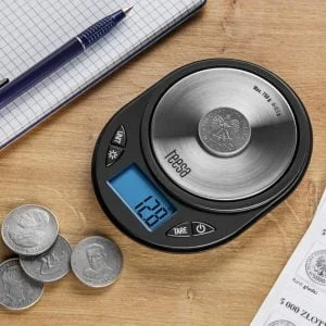 vaga, olovka i papir s novčićima na stolu